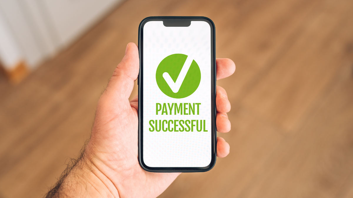 Męska dłoń z telefonem, na którego ekranie jest napis payment successful