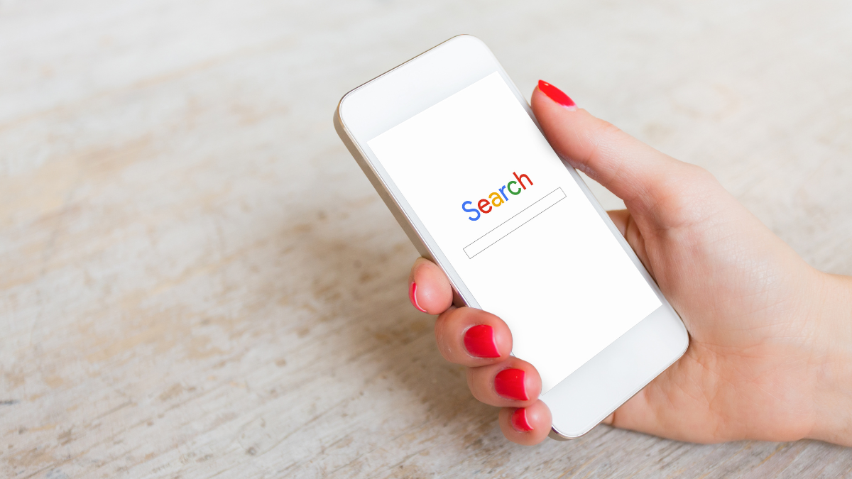 Kobieca ręka z telefonem, na którego ekranie jest przeglądarka Google