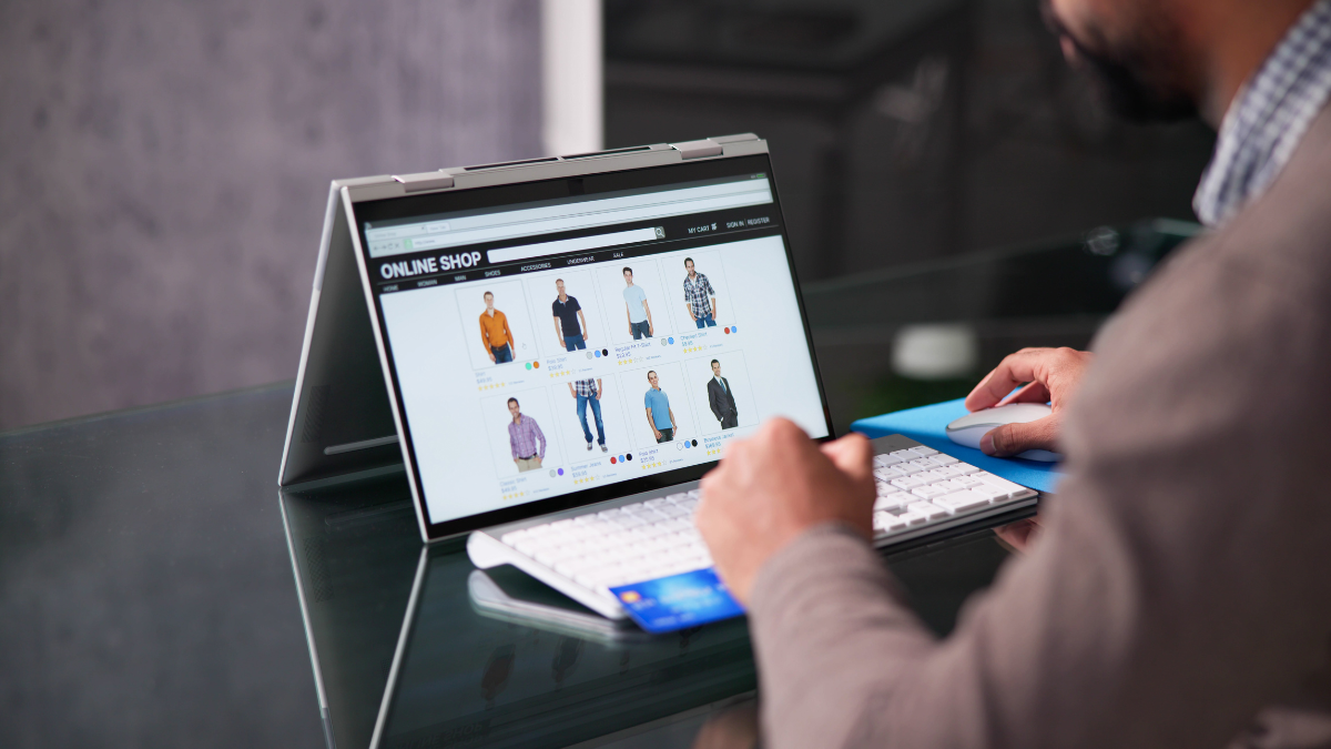 Mężczyzna z tabletem z klawiatura i myszką na biurku przeglądający asortyment sklepu online