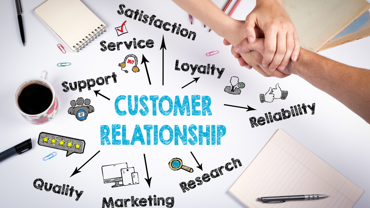 Uścisk dłoni dwóch osób na tle biurka z napisem customer relationship
