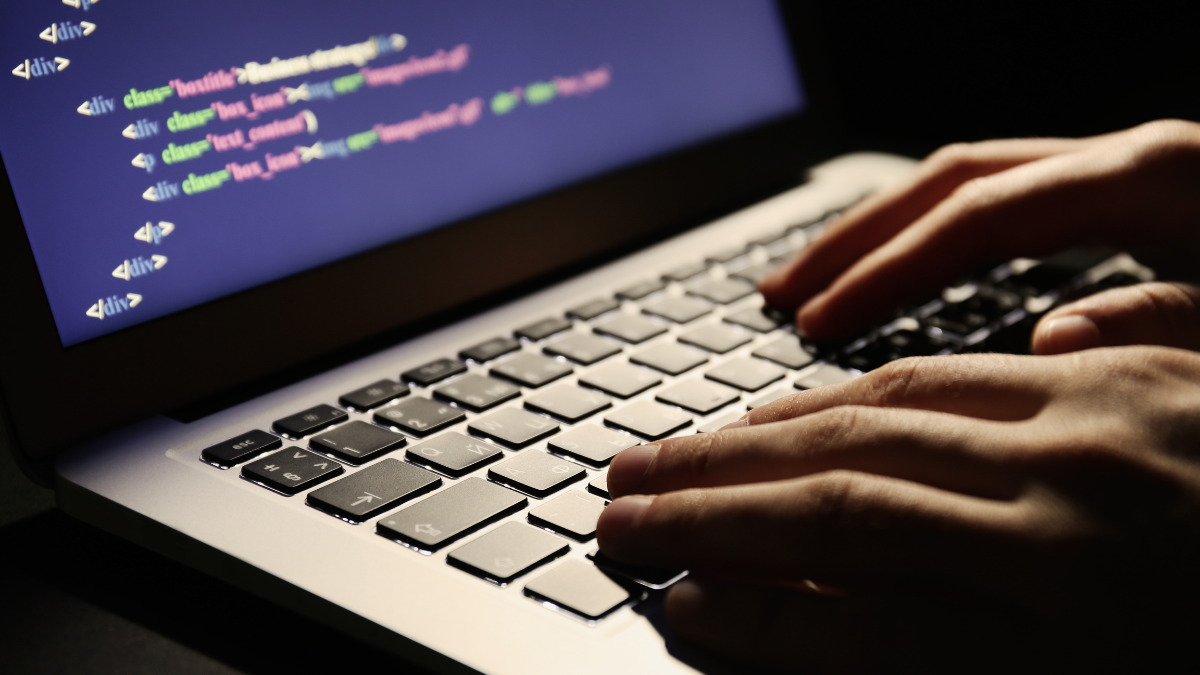 Mężczyzna piszący kod na klawiaturze laptopa