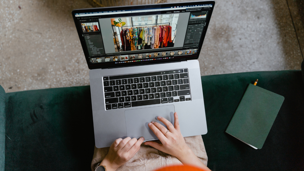 Widok z góry kobiety wybierającej na laptopie zdjęcia ubrań do sklepu e-commerce